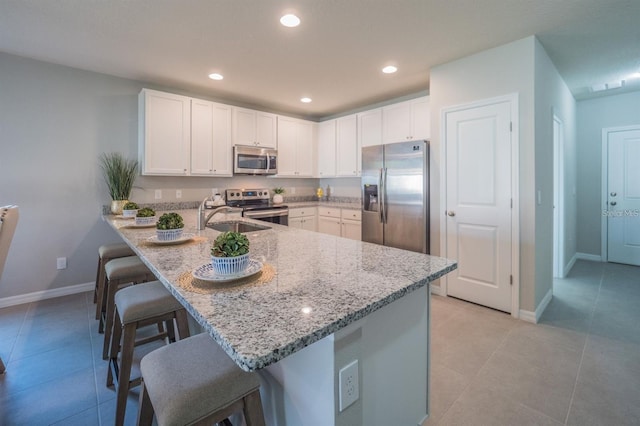848 San Pedro Ct, Kissimmee, FL 34758 - kitchen featuring a sink, a breakfast bar, a peninsula, stainless steel appliances, and light stone counters