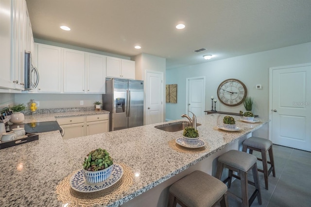848 San Pedro Ct, Kissimmee, FL 34758 - kitchen with a kitchen bar, visible vents, light stone counters, a sink, and stainless steel appliances