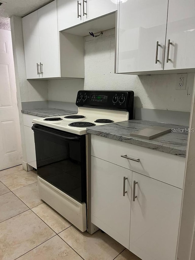 kitchen with white cabinets, light tile patterned floors, and range with electric stovetop