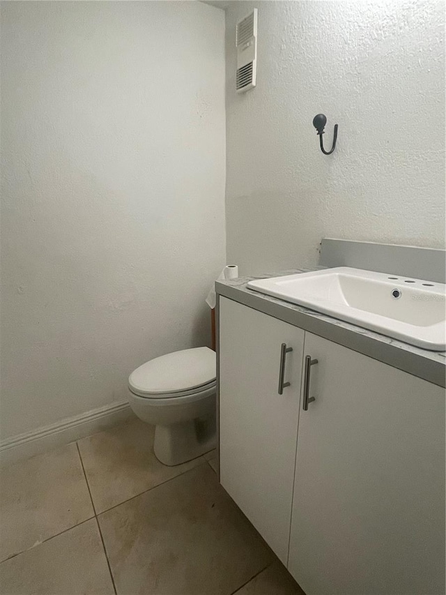 half bathroom with vanity, baseboards, tile patterned floors, toilet, and visible vents