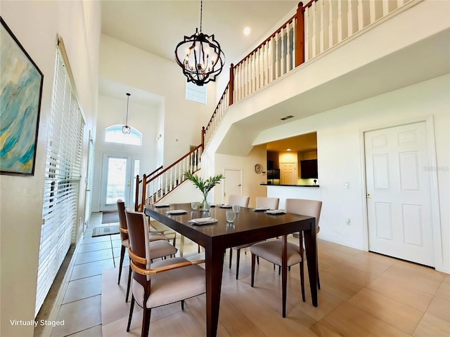 dining room with a chandelier, a towering ceiling, visible vents, and stairway
