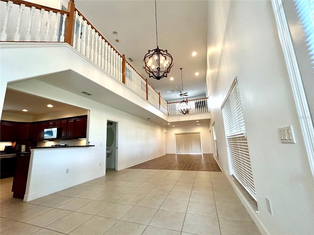 interior space with a chandelier, a high ceiling, light tile patterned flooring, dark countertops, and open floor plan