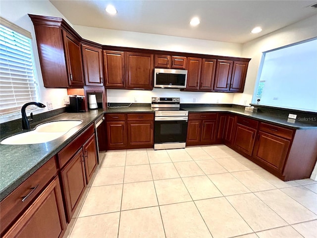 kitchen featuring light tile patterned floors, a sink, dark countertops, recessed lighting, and stainless steel appliances
