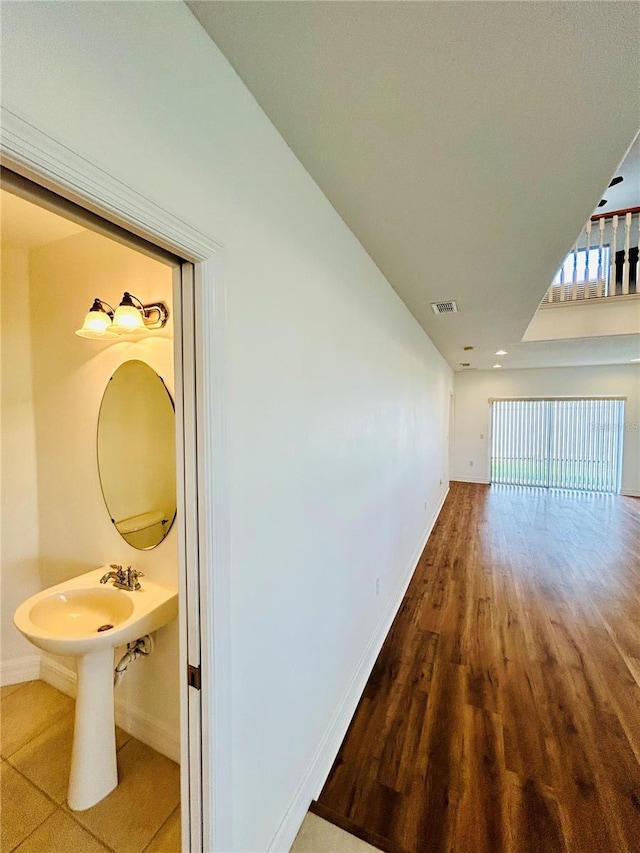 hallway featuring visible vents, baseboards, and wood finished floors