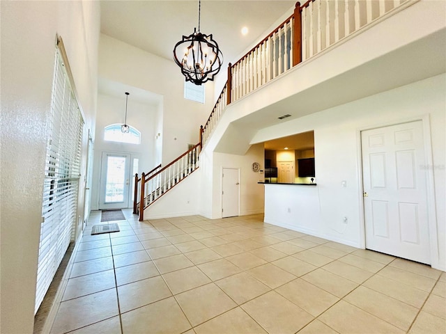 foyer featuring a chandelier, light tile patterned floors, a towering ceiling, and visible vents