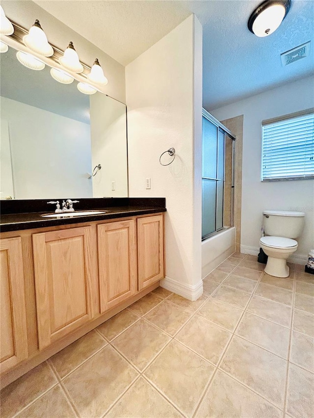 bathroom with a textured ceiling, shower / bath combination with glass door, tile patterned flooring, visible vents, and toilet