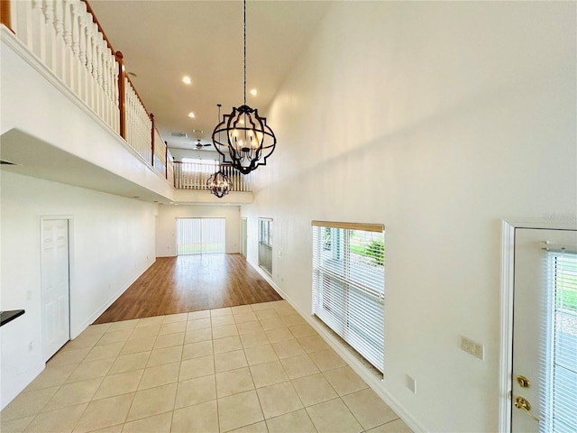 interior space with recessed lighting, a high ceiling, light tile patterned flooring, a notable chandelier, and baseboards