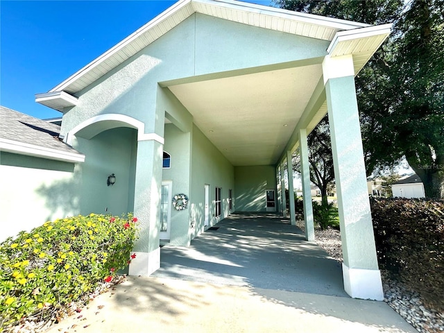 view of exterior entry with a carport and stucco siding