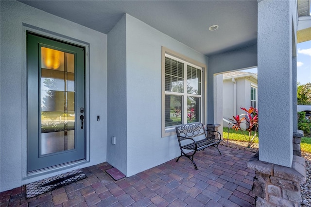 doorway to property with covered porch and stucco siding