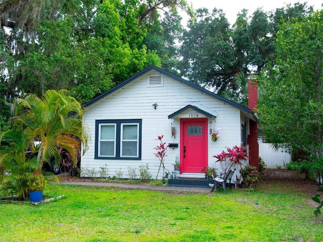 bungalow featuring entry steps, a front lawn, and a chimney