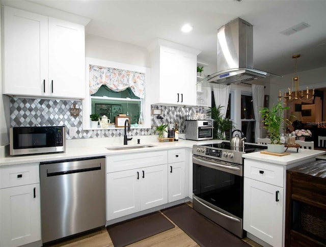 kitchen with a peninsula, visible vents, a sink, stainless steel appliances, and island range hood