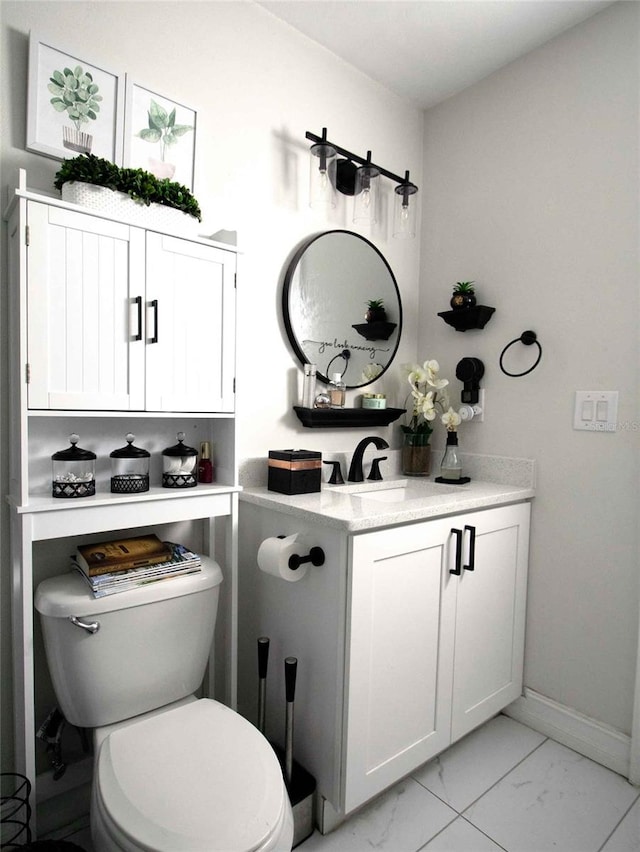 half bathroom with toilet, marble finish floor, baseboards, and vanity