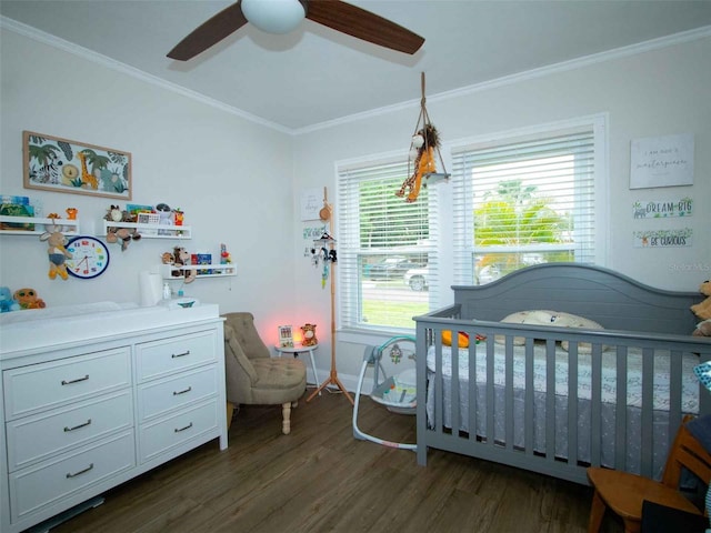bedroom with baseboards, a ceiling fan, a crib, dark wood-style floors, and crown molding