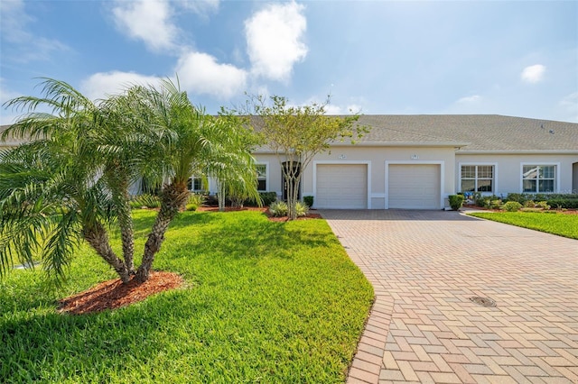 view of front facade featuring a front yard, an attached garage, decorative driveway, and stucco siding