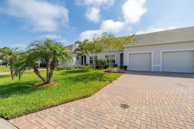 view of front facade featuring a front yard, an attached garage, decorative driveway, and stucco siding