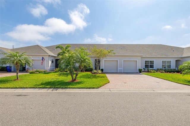 ranch-style home with a front lawn, an attached garage, decorative driveway, and stucco siding