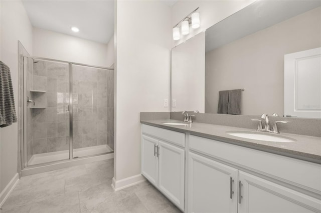 full bath featuring a sink, baseboards, double vanity, and a stall shower