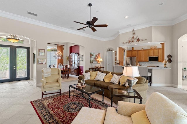 133 Torino Ln, Kissimmee, FL 34759 - living room with arched walkways, french doors, light tile patterned floors, ornamental molding, and a chandelier