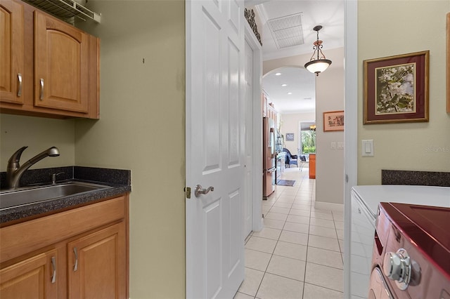 133 Torino Ln, Kissimmee, FL 34759 - washroom featuring washing machine and clothes dryer, arched walkways, light tile patterned floors, and cabinet space
