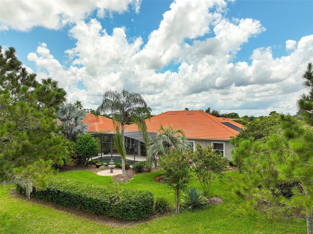 133 Torino Ln, Kissimmee, FL 34759 - rear view of property with a tile roof, glass enclosure, a yard, and stucco siding