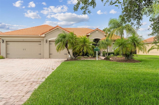 133 Torino Ln, Kissimmee, FL 34759 - mediterranean / spanish house with decorative driveway, a garage, a front yard, stucco siding, and a tile roof