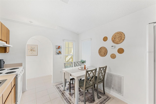 1560 Vista Lake Cir, Melbourne, FL 32904 - dining space with vaulted ceiling, light tile patterned floors, a textured ceiling, visible vents, and arched walkways