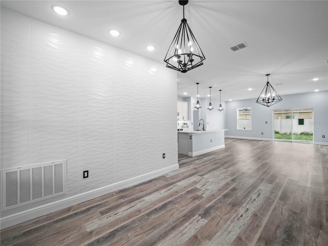 145 Willow Dr, Poinciana, FL 34759 - unfurnished living room featuring wood finished floors, a sink, a notable chandelier, and visible vents