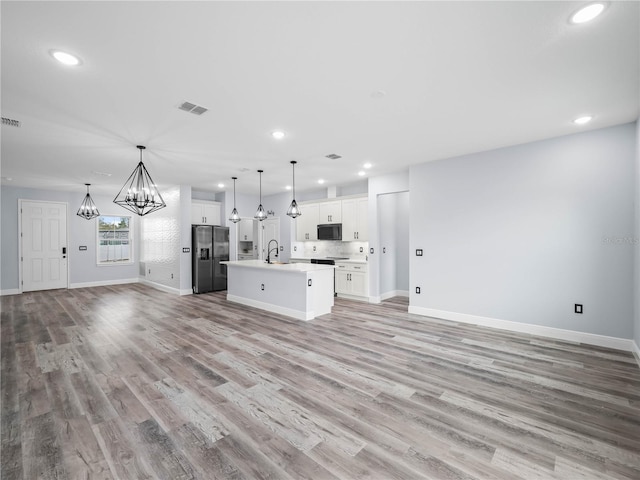 145 Willow Dr, Poinciana, FL 34759 - kitchen featuring black microwave, refrigerator with ice dispenser, visible vents, a chandelier, and open floor plan
