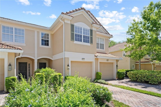 view of front of home featuring driveway, stucco siding, a tiled roof, and an attached garage