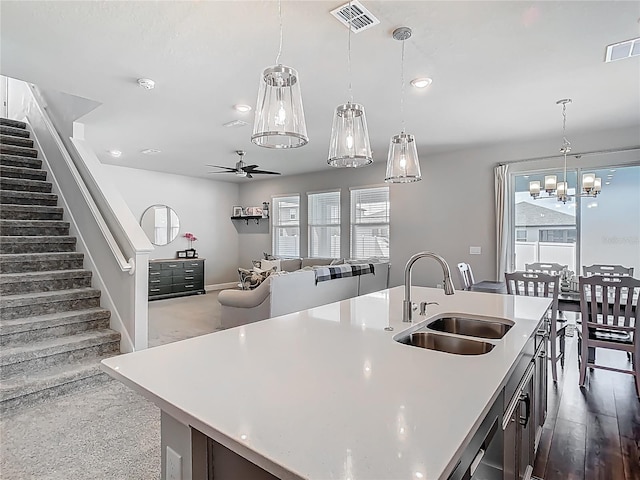 kitchen with light countertops, ceiling fan with notable chandelier, visible vents, and a sink
