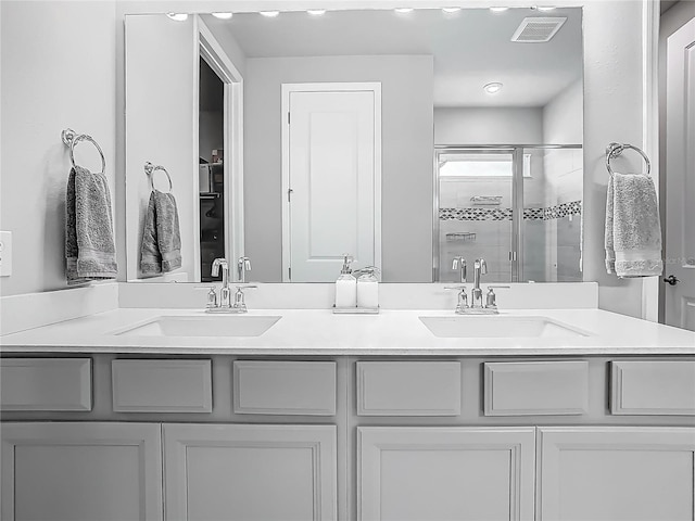 bathroom with visible vents, a sink, a shower stall, and double vanity