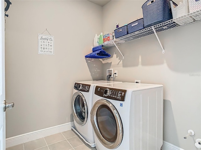 clothes washing area with baseboards, washer and dryer, laundry area, and light tile patterned floors