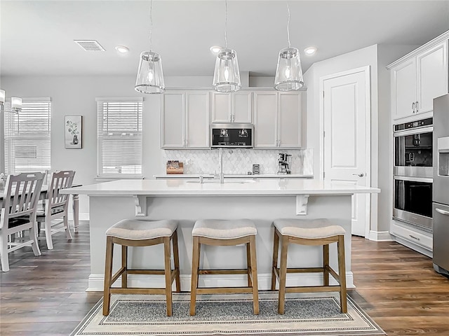 kitchen featuring light countertops, visible vents, a kitchen bar, and appliances with stainless steel finishes