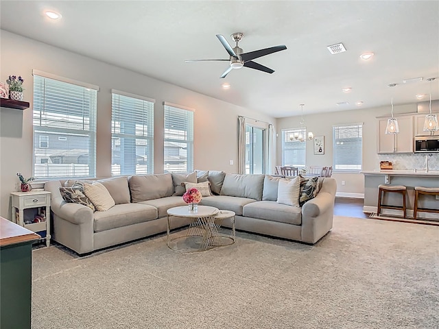 living area featuring baseboards, recessed lighting, visible vents, and ceiling fan with notable chandelier