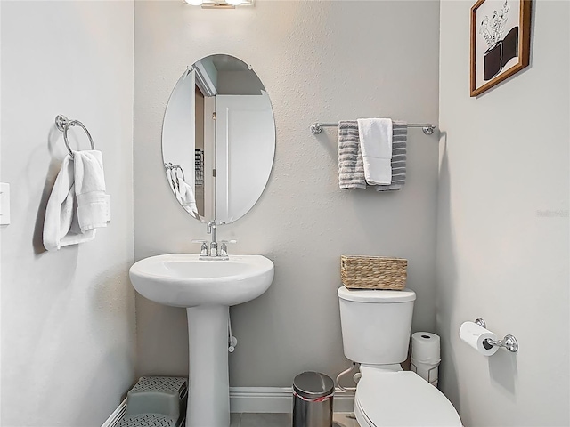 half bathroom featuring baseboards, a sink, and toilet