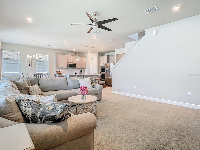 living area featuring recessed lighting, baseboards, visible vents, and ceiling fan with notable chandelier