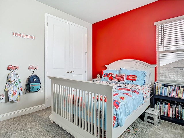 carpeted bedroom featuring a closet and baseboards