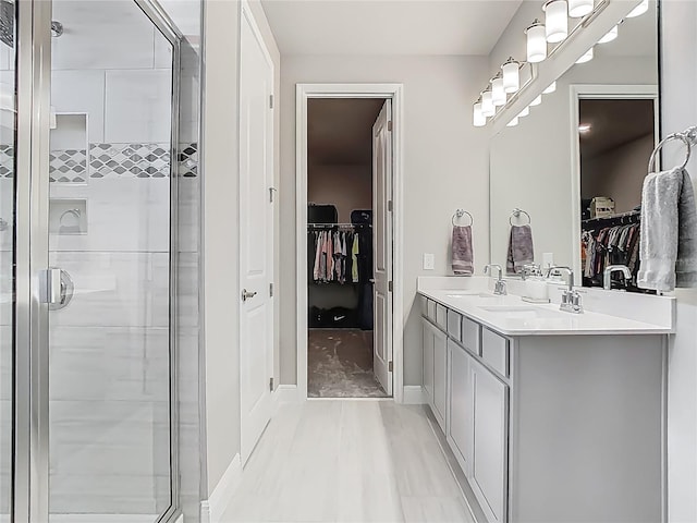bathroom with double vanity, a stall shower, and a sink