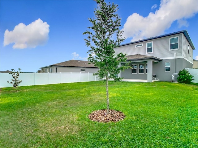rear view of property with stucco siding, a yard, central AC unit, and fence