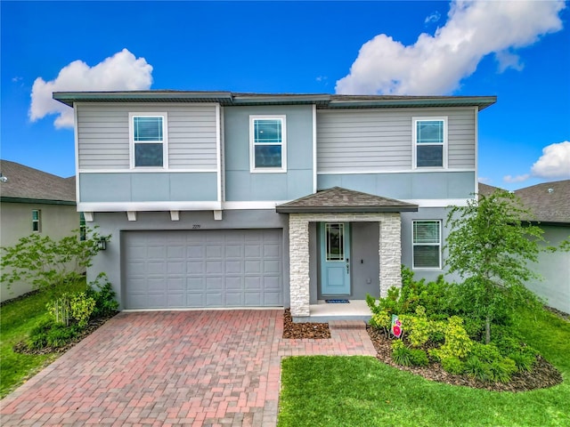 traditional-style home with an attached garage, stone siding, stucco siding, and decorative driveway