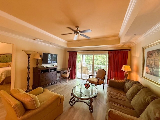 living room with ceiling fan, wood finished floors, ornamental molding, and a raised ceiling