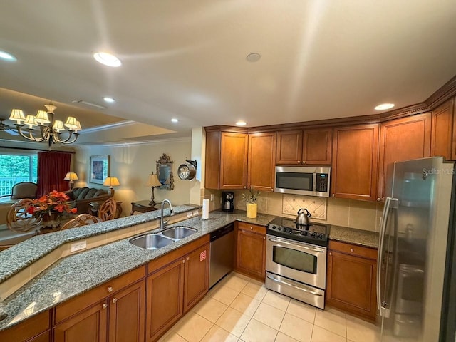 kitchen featuring a chandelier, brown cabinets, appliances with stainless steel finishes, and a sink