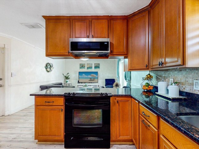 5123 Lighthouse Rd, Orlando, FL 32808 - kitchen with stainless steel microwave, black range with electric stovetop, dark stone counters, backsplash, and crown molding