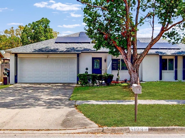 5123 Lighthouse Rd, Orlando, FL 32808 - mid-century home with a garage, roof mounted solar panels, concrete driveway, a front lawn, and a shingled roof
