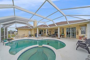 18011 Prairie Wolf Gln, Parrish, FL 34219 - view of swimming pool featuring glass enclosure, a pool with connected hot tub, and a patio area