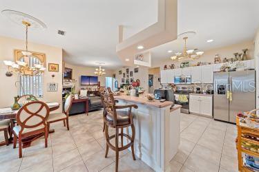 18011 Prairie Wolf Gln, Parrish, FL 34219 - kitchen with an inviting chandelier, light tile patterned floors, a kitchen bar, and stainless steel appliances