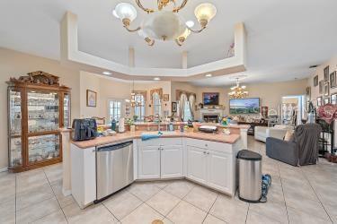 18011 Prairie Wolf Gln, Parrish, FL 34219 - kitchen with an inviting chandelier, a raised ceiling, white cabinetry, open floor plan, and stainless steel dishwasher