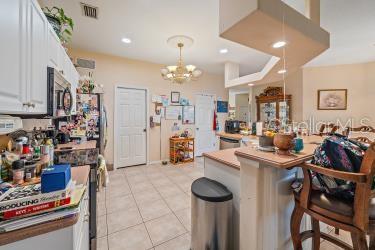 18011 Prairie Wolf Gln, Parrish, FL 34219 - kitchen featuring white cabinets, light tile patterned flooring, appliances with stainless steel finishes, light countertops, and a kitchen breakfast bar