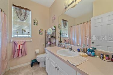 18011 Prairie Wolf Gln, Parrish, FL 34219 - full bath with vanity, tile patterned flooring, toilet, and curtained shower