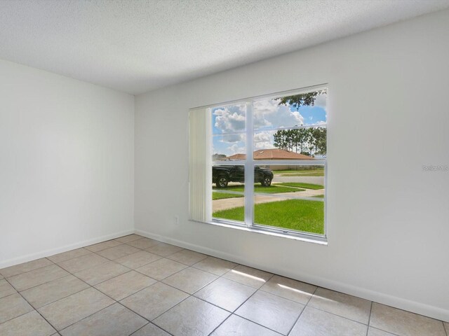 12513 Indiana Woods Ln, Orlando, FL 32824 - unfurnished room featuring plenty of natural light, a textured ceiling, light tile patterned floors, and baseboards